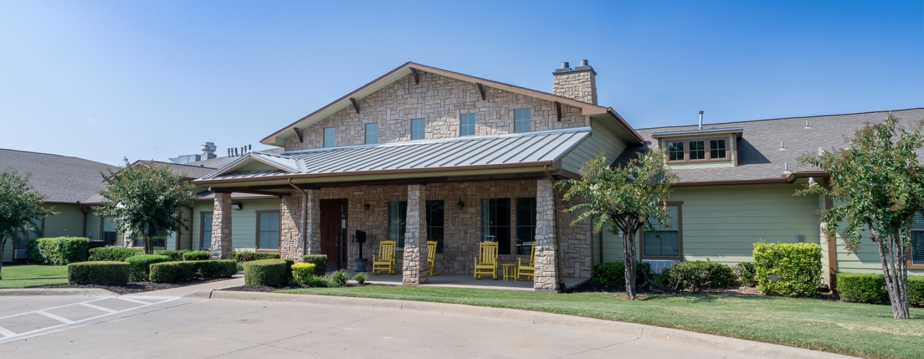 a brick building with yellow rocking chairs on the front porch